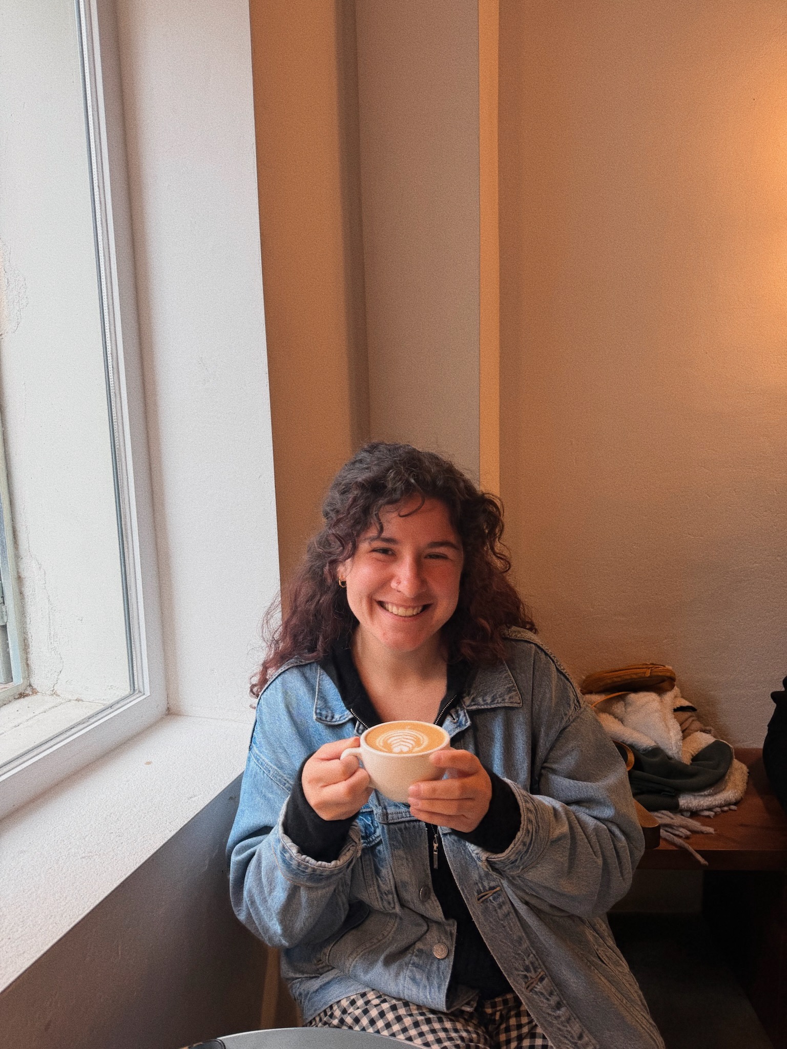 Ellie holding a latte by a window
